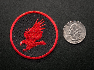 Circular embroidered badge with red CadSoft eagle logo on black background with red trim. Shown next to a quarter for scale. 