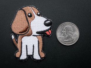 Embroidered badge in the shape of sitting BeagleBone dog.Dog is brown and white with red detail for tongue. Shown next to a quarter for scale.  