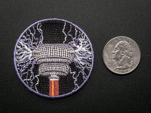 Circular embroidered badge with tesla coil machine in copper and grey shooting out lavender and white brush discharges on a black background, trimmed in lavender edge. Shown next to a quarter for  scale 