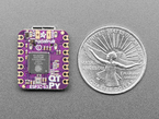 Back of small purple, square-shaped microcontroller next to US quarter for scale.