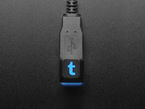 Overhead shot of a chonky USB cable adapter with a black keycap. The keycap is etched with the Tumblr logo and glows blue.