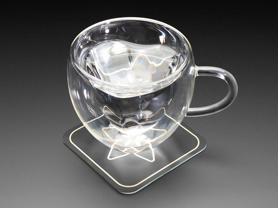 Angled shot of a clear mug with water on top of coaster.