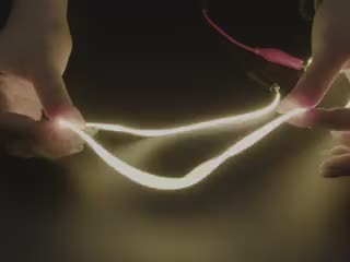 Video of two hands playing with a 600mm long LED filament glowing warm white light.