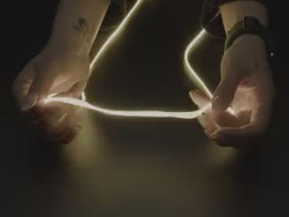 Hands playing with a 1.2m long LED filament glowing warm white light.