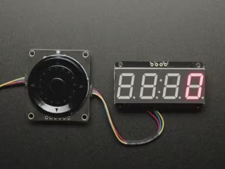 Overhead video of a blue-manicured finger manipulating a rotary encoder connected to a 4-digit LED segment display. 