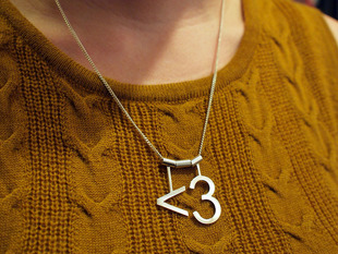 model wearing silver necklace with "<3" heart symbol 