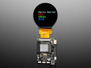 Overhead shot of TFT driver board connected to a round TFT display, which says, "Hello world!"