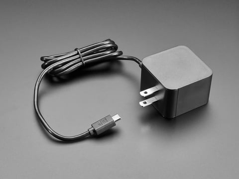 Angled shot of black, square-shaped power supply block with a coiled black cable.