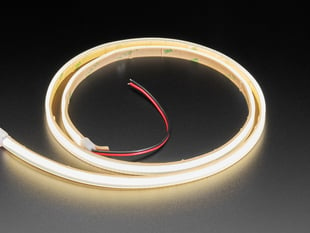 Angled shot of 1m long coiled LED strip, lit up with warm LEDs.