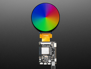 Overhead shot of a 2.8" round TFT screen connected to a microcontroller. The screen displays a colorful rainbow gradient.