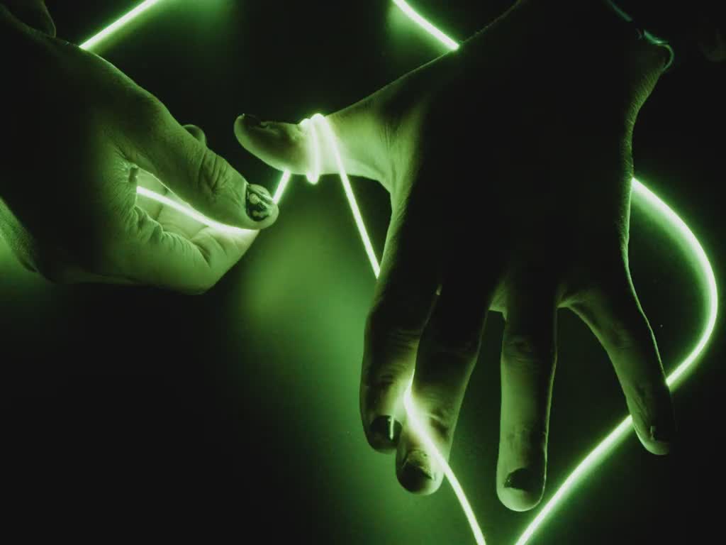 Video of Black hands playing with a long piece of green LED filament.