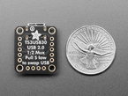 Back of black, square, breakout board next to US quarter for scale.