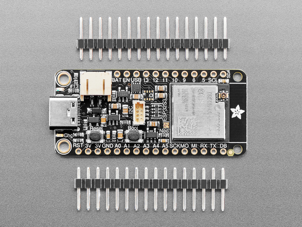 Overhead shot of black, rectangular microcontroller between two pieces of 16-pin header.