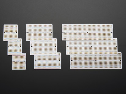 Top view of three packs of three different sized Adafruit Perma Proto-Board PCBs.