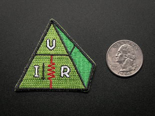 Embroidered triangle-ish shaped badge of a green pyramid with the letters V, I, and R in white, with a red zigzag resister, and trimmed in black. Shown next to a quarter for scale. 