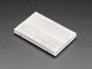 Angled shot of half-size solderless breadboard with red and black power lines.
