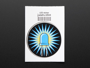 Circular sticker of blue LED with rays of blue light over a yellow corona on black background. Sticker is mounted on white paper with barcode. 