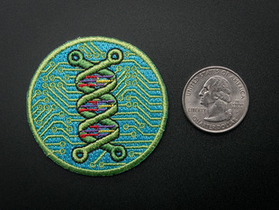 Circular embroidered badge showing a green double helix over an abstracted blue and green circuitboard design. Badge is trimmed in green and shown next to a quarter for scale. 