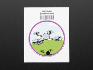 Circular sticker showing a small grey drone over a stylized blue sky, with white clouds, and green grass. Badge is trimmed in purple. Mounted on white paper with barcode.  