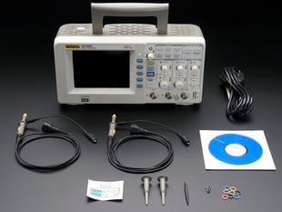 Oscilloscope with probes detached surrounded with accessories.