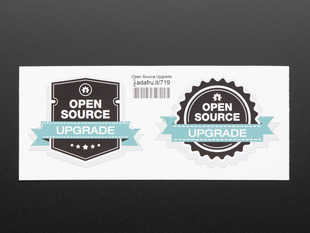 photograph of two black stickers, one shield shaped, the other gear shaped, with white lettering reading "open source" with a turquoise banner running across each reading "upgrade" both stickers are mounted on white paper with barcode. 