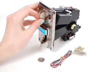 Hand inserting quarter into coin mechanism slot with hardware and wires nearby