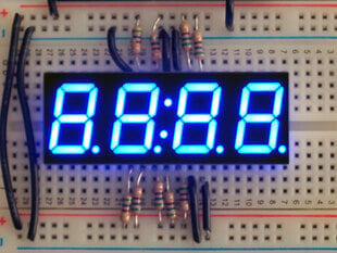 Overhead shot of a blue LED module assembled on a breadboard with resistors flashing 88:88.