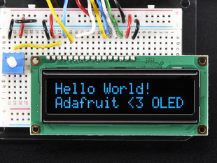 Wired up 16x2 OLED with blue on black text "Hello World! Adafruit <3 OLED"