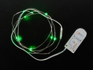 Coil of thin flexible wire with lit up embedded green LED 'fairy' lights attached to battery holder