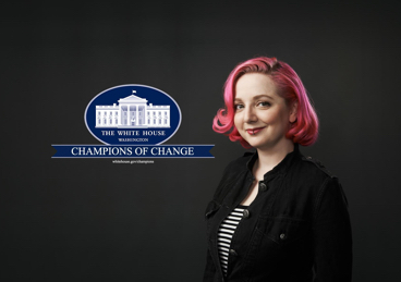 Woman with pink hair standing in front of White House Champions of Change logo
